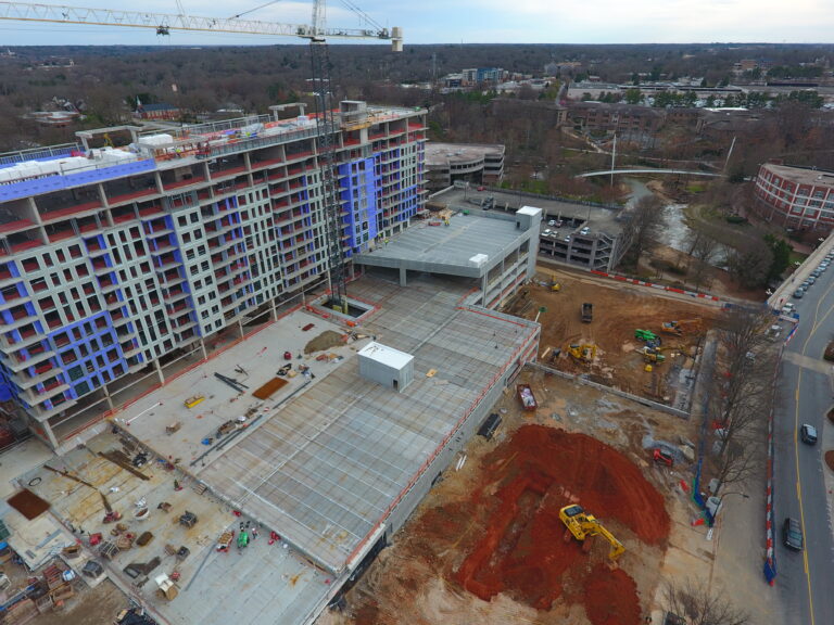 Aerial view of a mixed-use facility construction site in downtown Greenville with heavy machinery and materials on the ground.