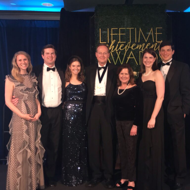 Group of seven individuals dressed in formal attire at a lifetime achievement award event honoring an Auburn University executive.