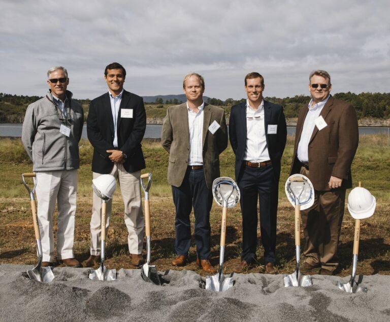 Five men in business attire holding shovels at a groundbreaking ceremony.