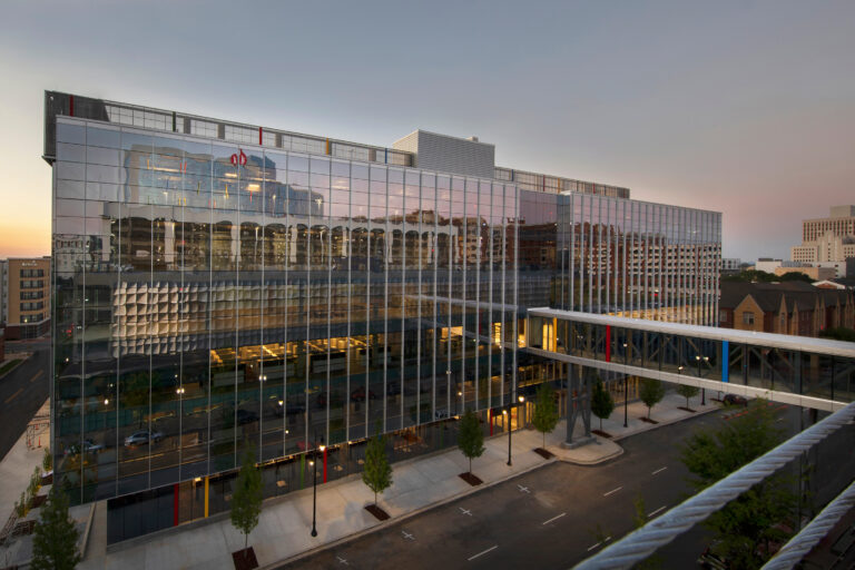 Modern glass building facade reflecting the warm hues of sunset in an urban setting.