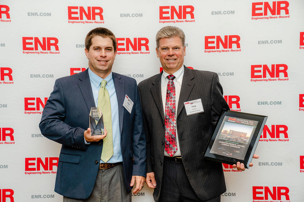 Two men in business attire holding an award and a plaque at an event by ENR Southeast.