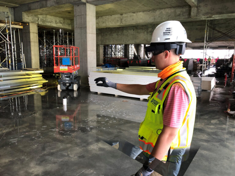 Construction worker in high-visibility vest and hard hat gesturing on a construction site, showcasing the future of construction.