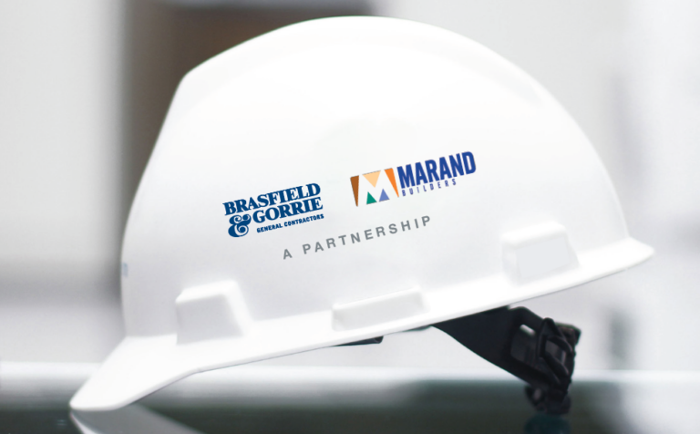 A white hard hat with the logos of brasfield & gorrie and marand builders indicating a partnership.