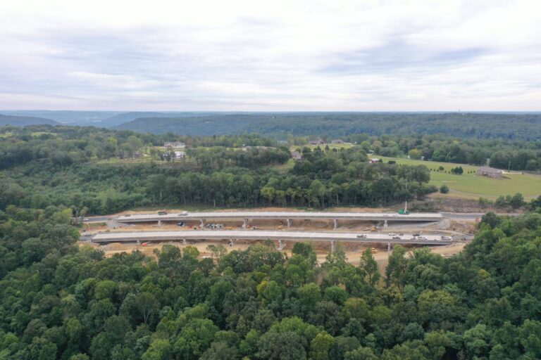 Aerial view of a construction site with equipment alongside a forested area.