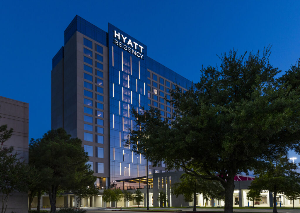 Exterior view of the Hyatt Regency hotel at twilight with illuminated windows and signage, a notable Brasfield & Gorrie project.