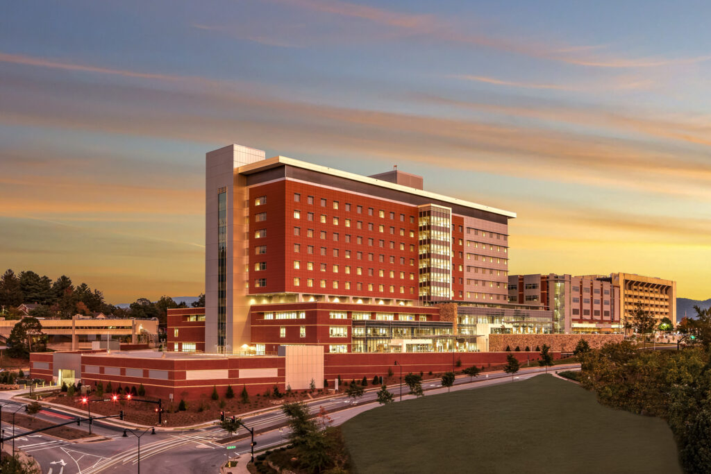 Modern hospital complex at twilight with illuminated windows and exterior lights, featured in ENR Southwest.