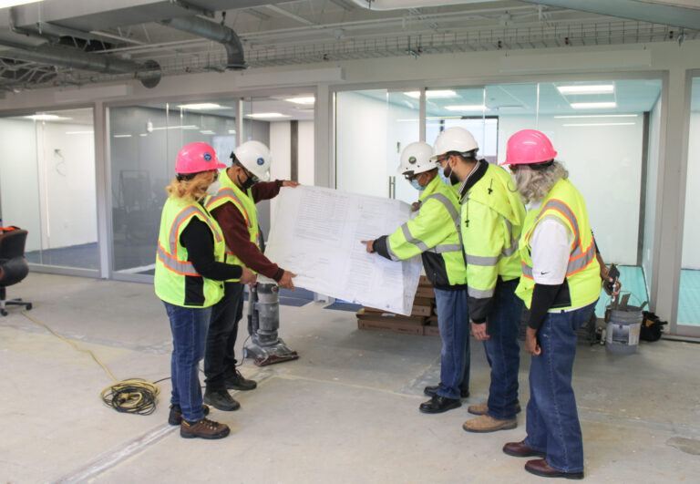 Construction workers reviewing blueprints together at a job site.