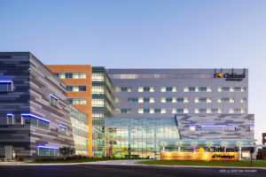 Modern hospital building exterior at dusk with illuminated signage, featured in an Award Spotlight by trade publications.