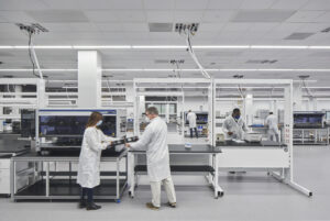 Researchers in lab coats working in a modern, well-equipped laboratory environment, spotlighted in trade publications.