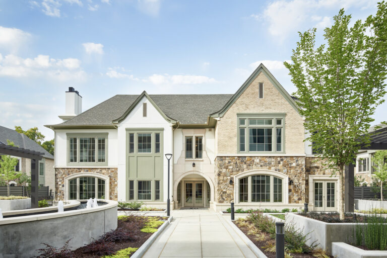 New traditional stone and stucco house at Kingsboro at Lenbrook with landscaped garden and clear skies.