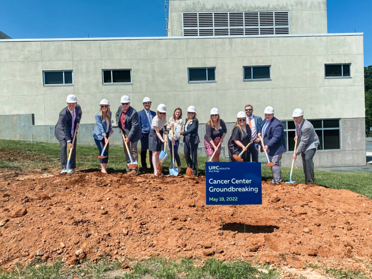 Group of individuals in hard hats participating in a groundbreaking ceremony for a cancer center on may 18, 2022.