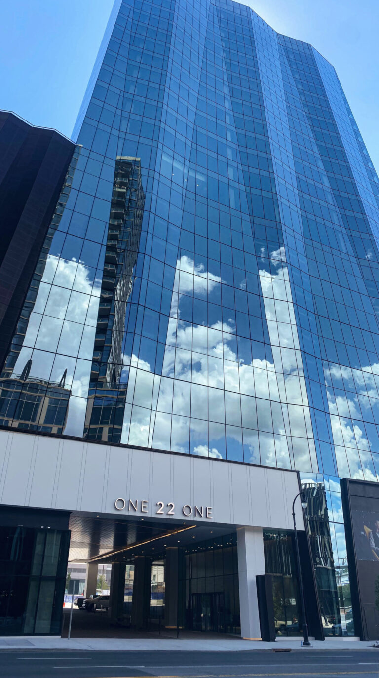 Modern glass skyscraper in Nashville's Gulch with cloud reflections and 