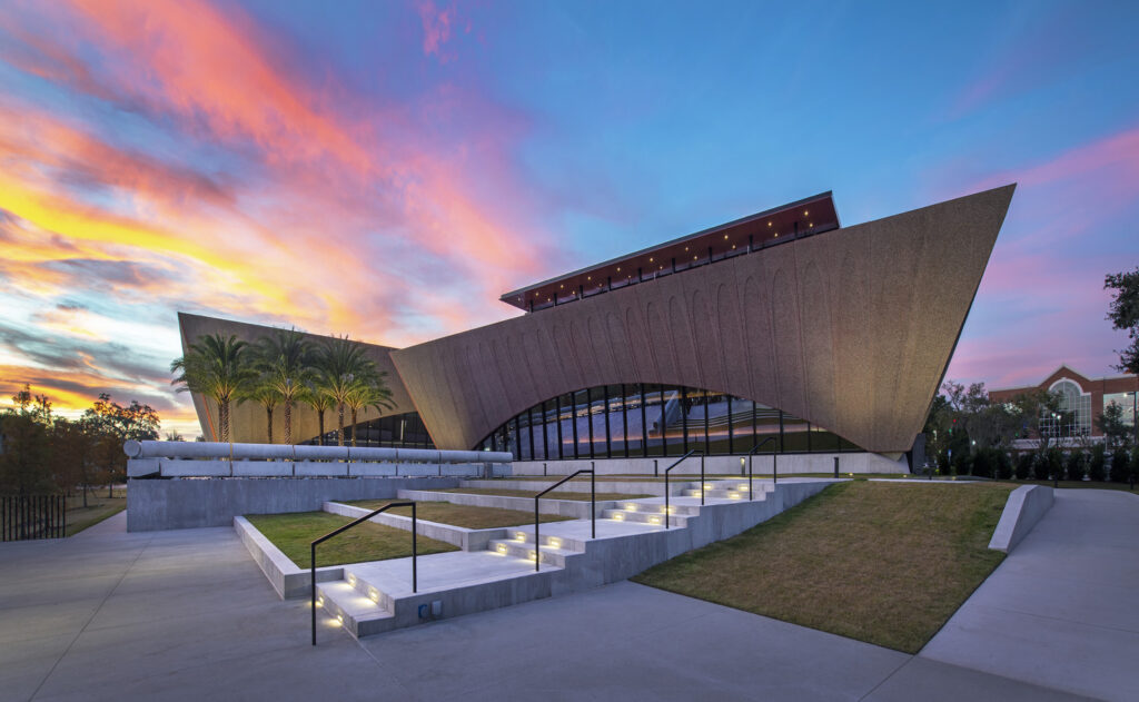 Modern architectural building, honored in ENR projects, with a unique angled roof under a vibrant sunset sky.