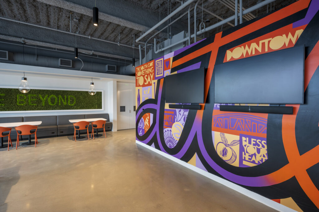 Modern office break room honored with colorful murals and casual seating areas.