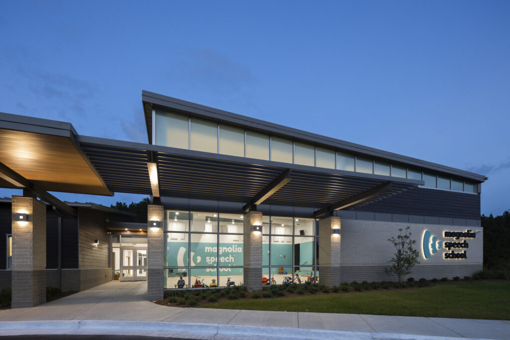 Modern educational building facade, Wins Magnolia Speech School Excellence in Construction Award, at dusk with illuminated interior and exterior lights.