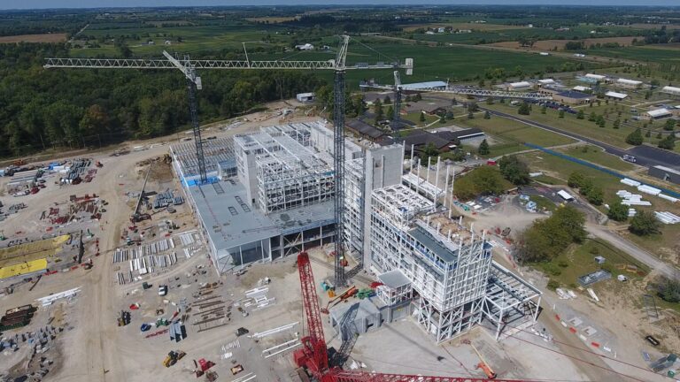 Aerial view of a large construction site with cranes and a partially completed building structure, showcasing innovative technology.
