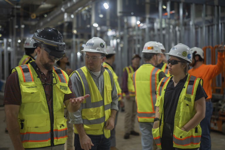 Workers in safety gear, recognized by Brasfield & Gorrie, discussing inside an industrial facility.