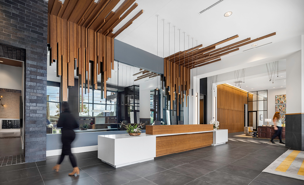 Modern lobby interior with wooden slats design features, reception desk, and person walking through the Midtown Union area.