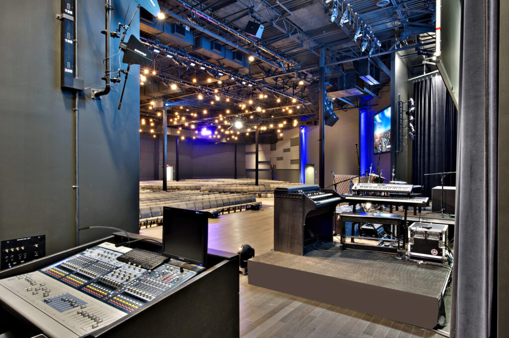 Sound mixing board overlooking an empty theater, now a converted space offering opportunities for developers, with stage lighting and seating.