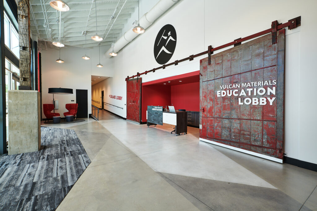 Modern lobby with industrial design featuring red accents and sliding metal doors, developed as vulcan materials education lobby.