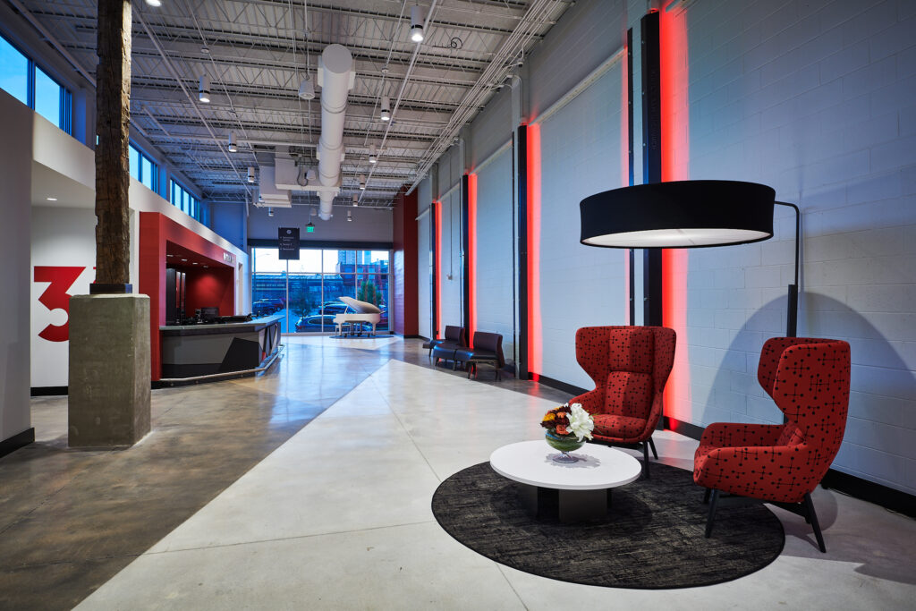 Modern office lobby with red accent lighting, comfortable seating, and a reception desk designed for developers and their collaborative opportunities.