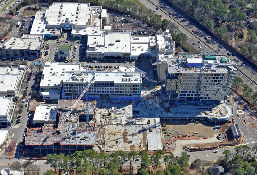 Aerial view of a construction site in North Hills with a partially completed building, adjacent to existing buildings and a parking lot, celebrates a construction milestone.