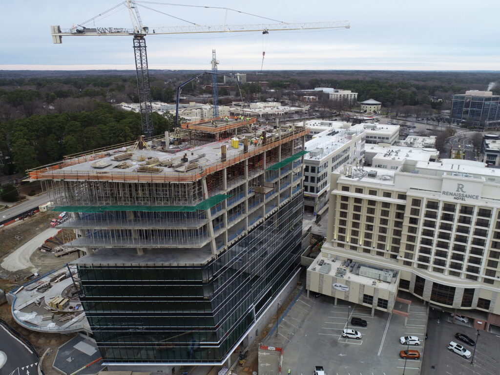 Aerial view of the One North Hills construction milestone, featuring a multi-story building under development with cranes and the surrounding urban landscape.