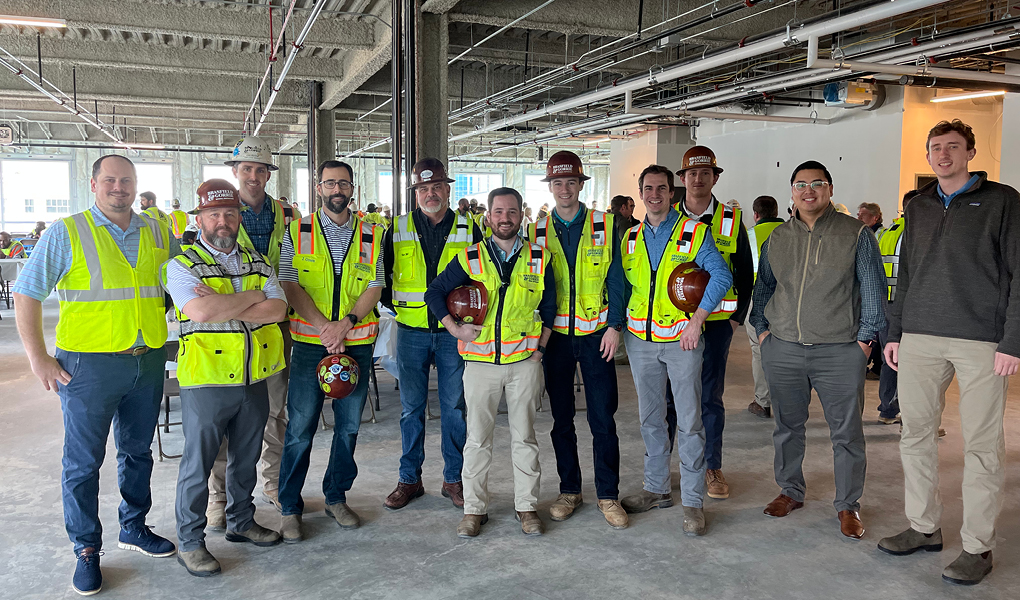 Construction team posing together in high-visibility vests and hard hats inside a building under construction to celebrate a Construction Milestone at One North Hills.
