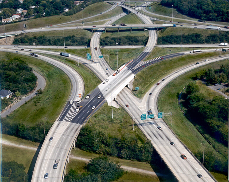 Aerial view of a complex multi-level highway interchange with vehicles in motion.