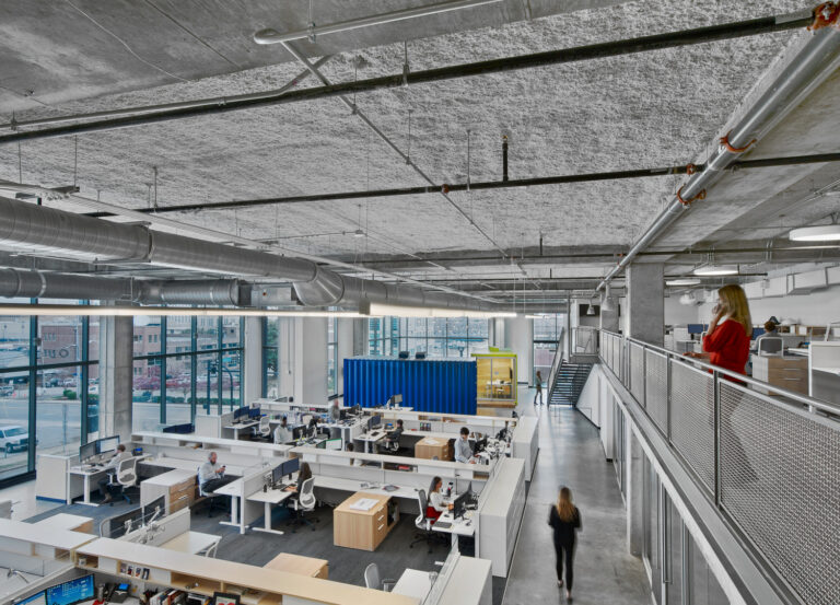 Modern open-plan office in Nashville, Tennessee with exposed ceiling and employees at workstations.