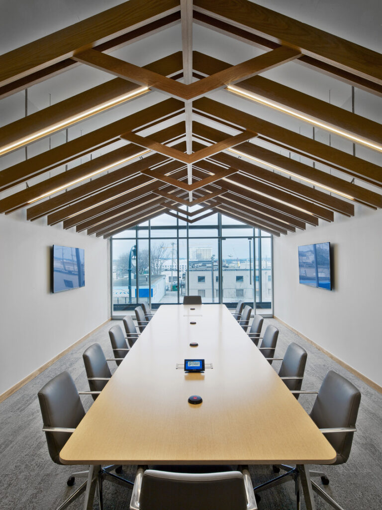 Modern conference room with a long table, chairs, wooden ceiling design, and large windows, inspired by the Nashville music scene.