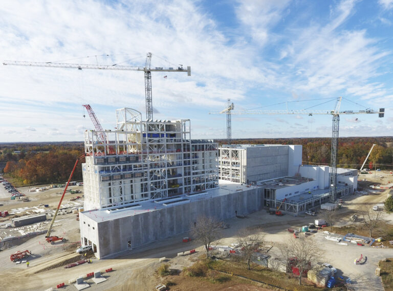Aerial view of a large industrial construction site with multiple cranes and a partially completed building.