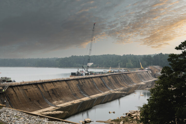 A large crane on a dam under a cloud-covered sky, utilized in heavy/civil construction.