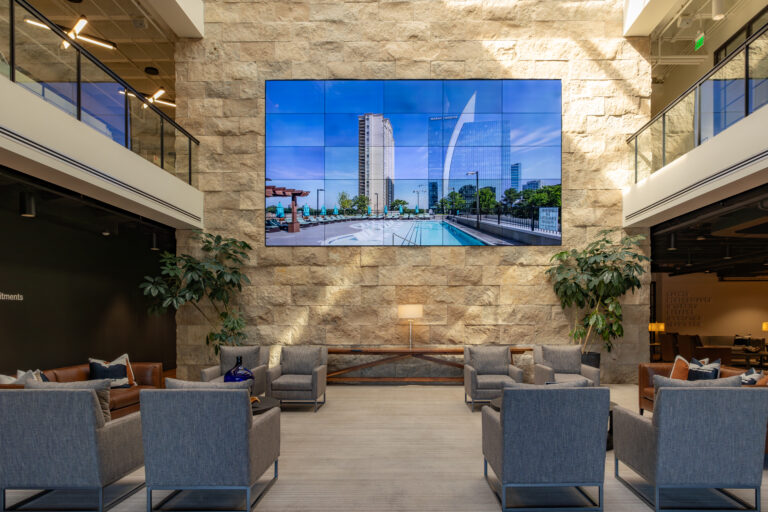 Modern office lobby with seating area and a large digital display screen showcasing an urban landscape.
