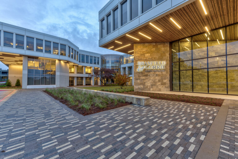 Modern office building entrance with landscaped pathway at dusk.