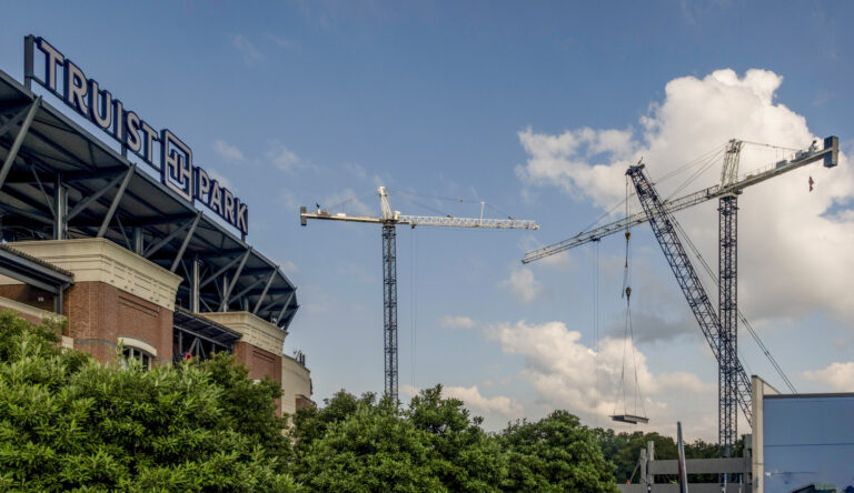 Construction cranes operating near truist park under a clear sky.