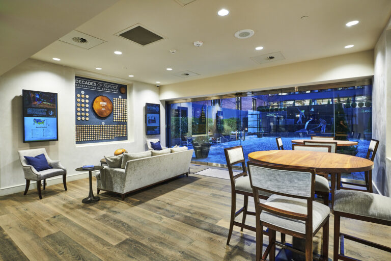 Modern lounge area in Birmingham with comfortable seating and informational wall displays, adjacent to a pool area visible through large glass windows.