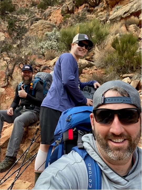 Three hikers taking a selfie on a mountain trail.