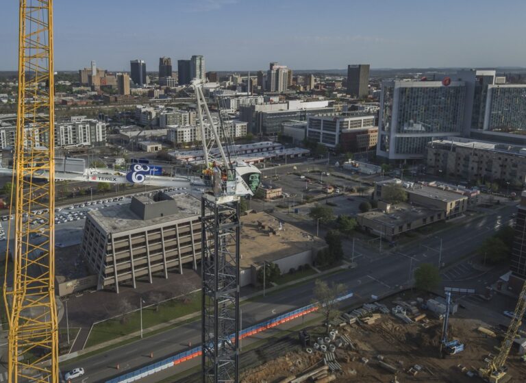 Aerial view of an urban construction site in Birmingham, Alabama, with surrounding buildings and a crane.
