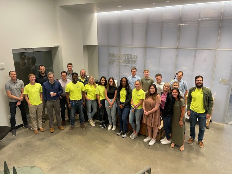 Group of colleagues in an office environment in Nashville, some wearing bright yellow shirts, posing together for a photo.