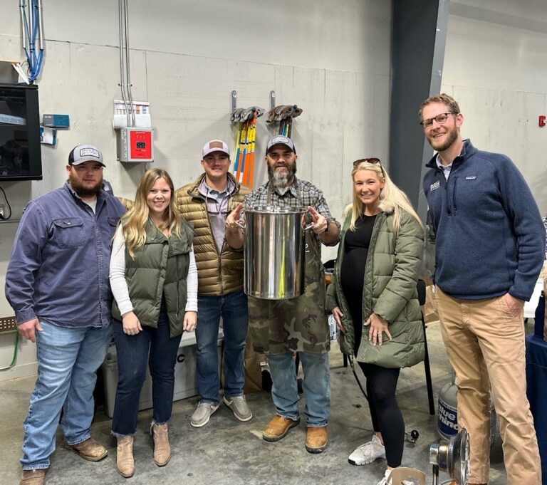 Group of people posing with a cylindrical metallic object in an industrial setting in Jackson, Mississippi.