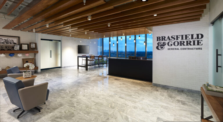 Modern office lobby in Dallas, Texas with a Brasfield & Gorrie logo, sleek furniture, and large windows overlooking a scenic view.