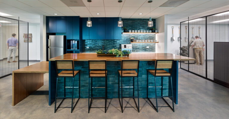 Modern office kitchen in Dallas, Texas, with blue cabinets, a seating island, and integrated appliances.