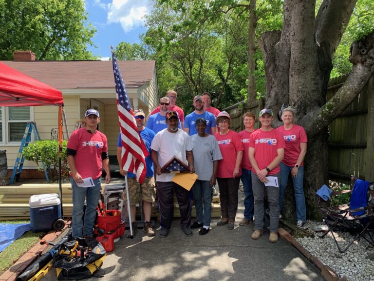A group of volunteers posing together with an american flag during a community event or project.