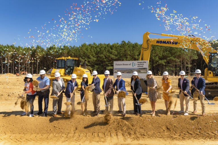 Group of people in hard hats at a groundbreaking ceremony with confetti in the air.