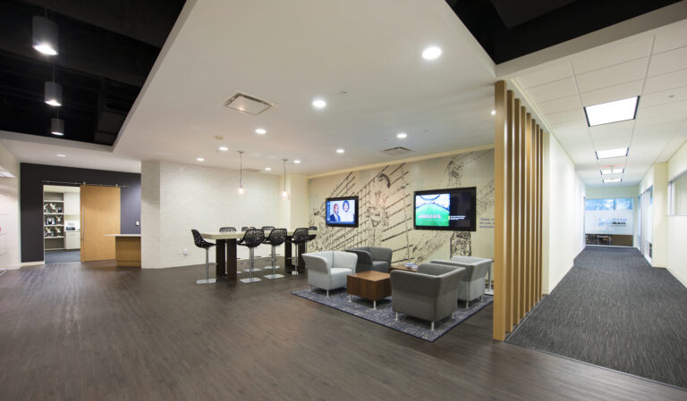 Modern office waiting area with seating, a tv display, and a refreshment counter.