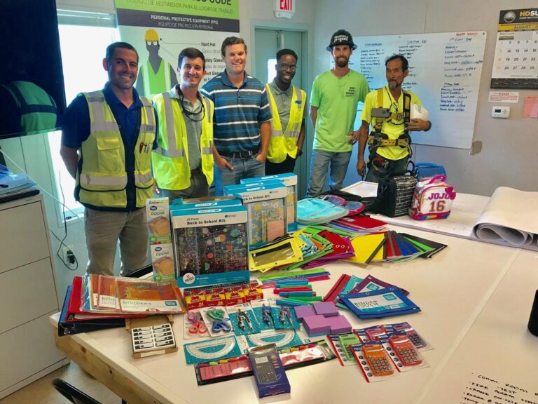 Group of construction workers with school supplies for a donation drive.