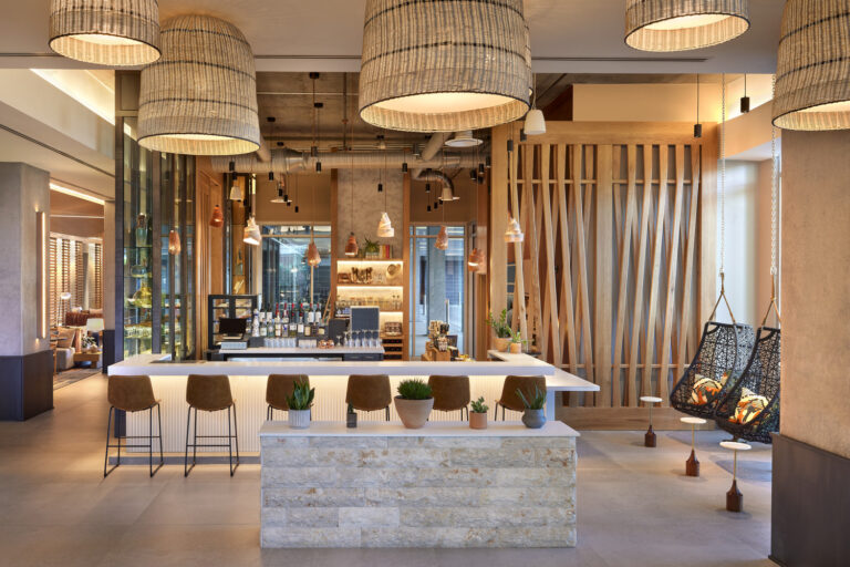 Modern commercial hotel lobby with a bar counter, pendant lighting, and comfortable seating areas.