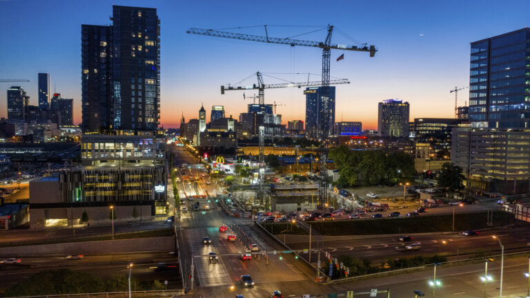 Twilight over a bustling cityscape in Nashville, Tennessee, with construction cranes towering above a developing urban area.