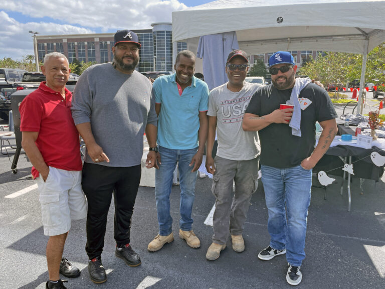 Five men smiling for a photo at an outdoor event in Orlando, Florida, possibly a tailgate or casual gathering.
